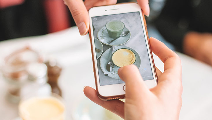 Zwei Kaffeetassen werden von einem Smartphone fotografiert