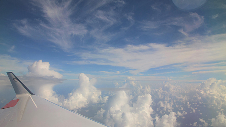 Wolken mit einem Flugzeugflügel im Vordergrund