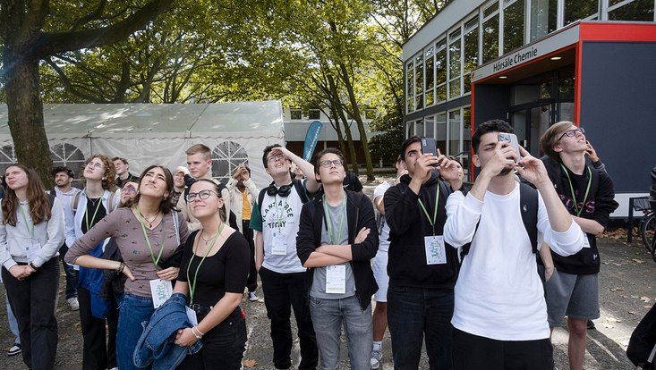 Schülerinnen die Fotos mit ihren Handys machen.