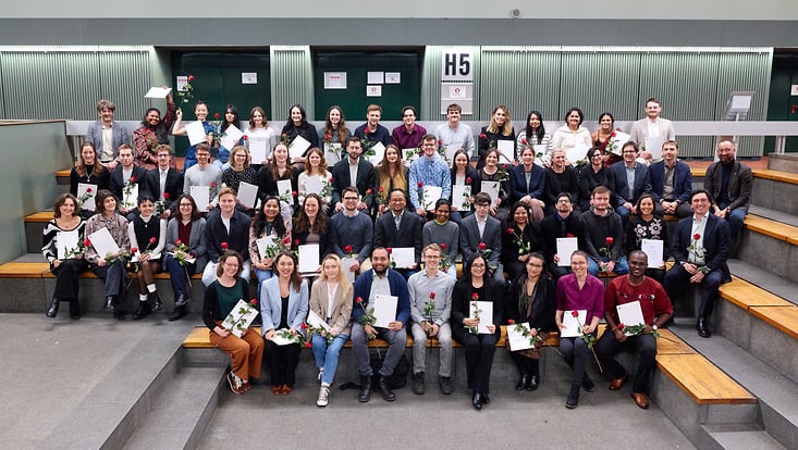 Gruppenbild der Graduierten mit ihren Urkunden und Rosen.