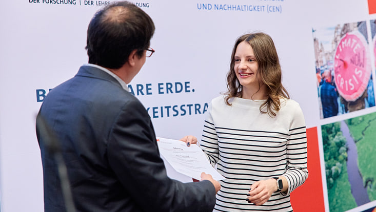 Prof. Felix Ament übergibt einer Master-Absolventin ihre Urkunde.