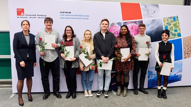 Prof. Johanna Baehr mit sieben Master-Absolvent:innen, die jeweils ihre Urkunde und eine Rose in den Händen halten.