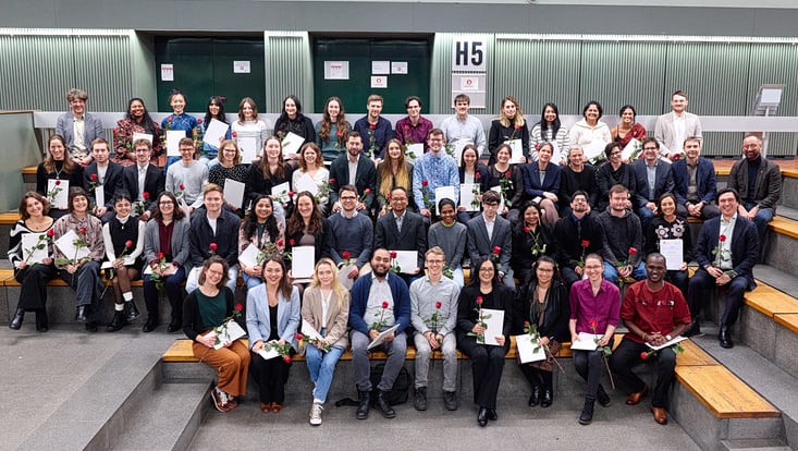 Gruppenbild der Graduierten mit ihren Urkunden und Rosen.