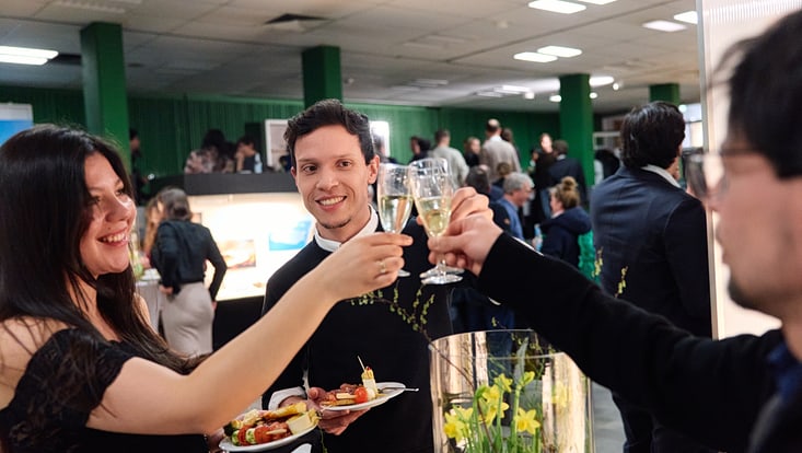 Drei Absolvent:innen stoßen mit Sekt an.